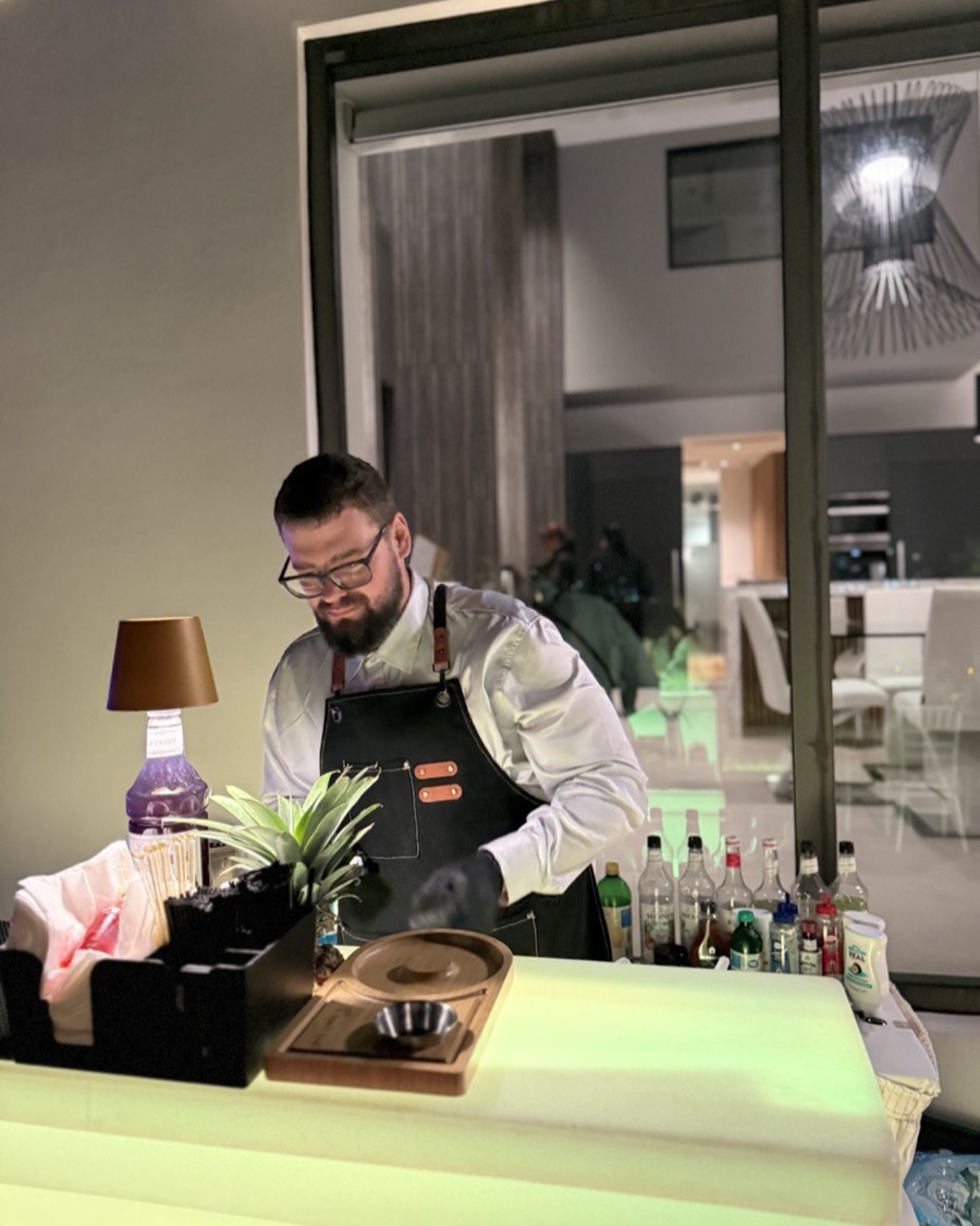 Bartender behind LED lit bar preparing mocktails Miami event