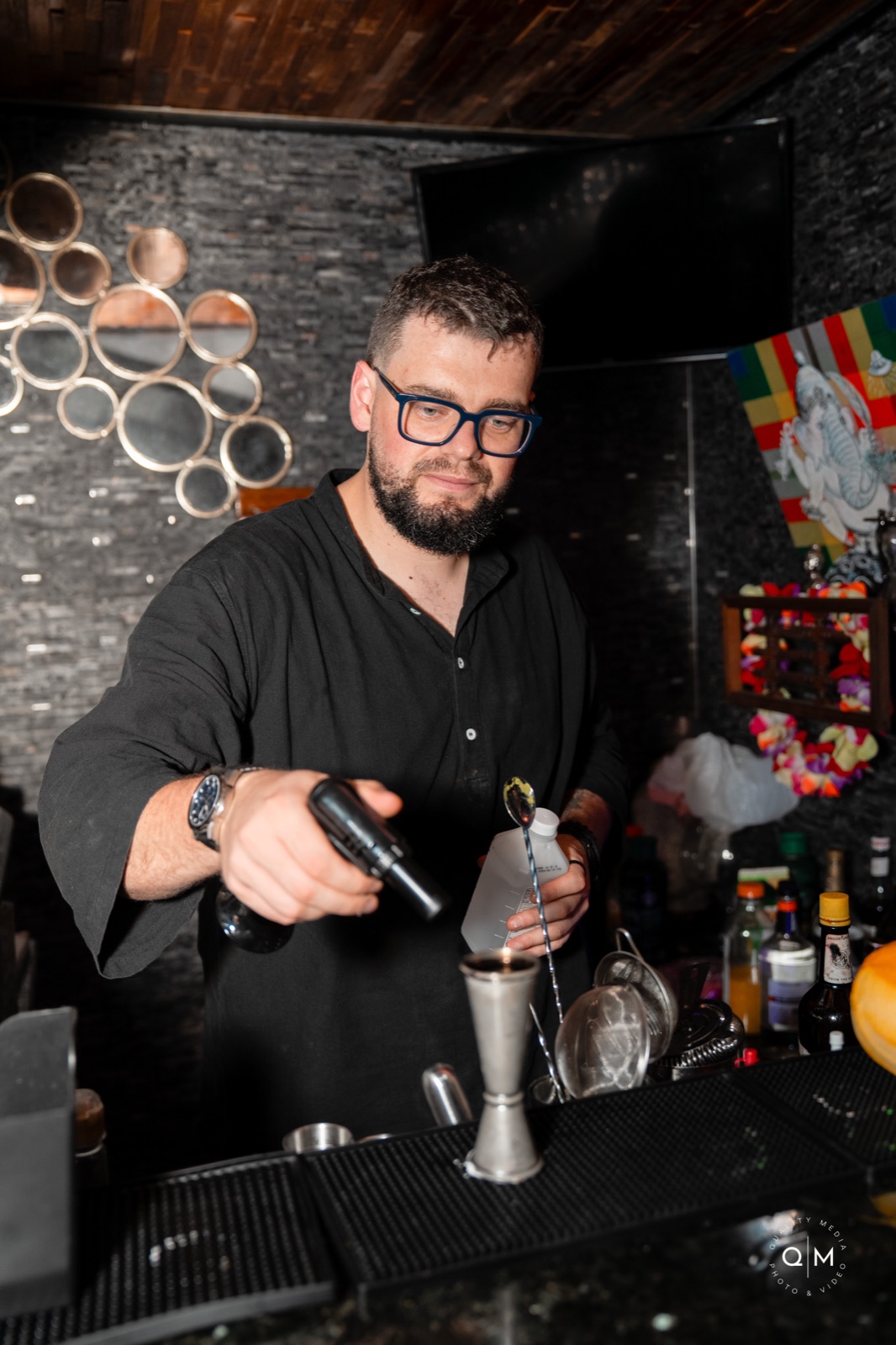 Bartender stirring a cocktail in a dimly lit bar