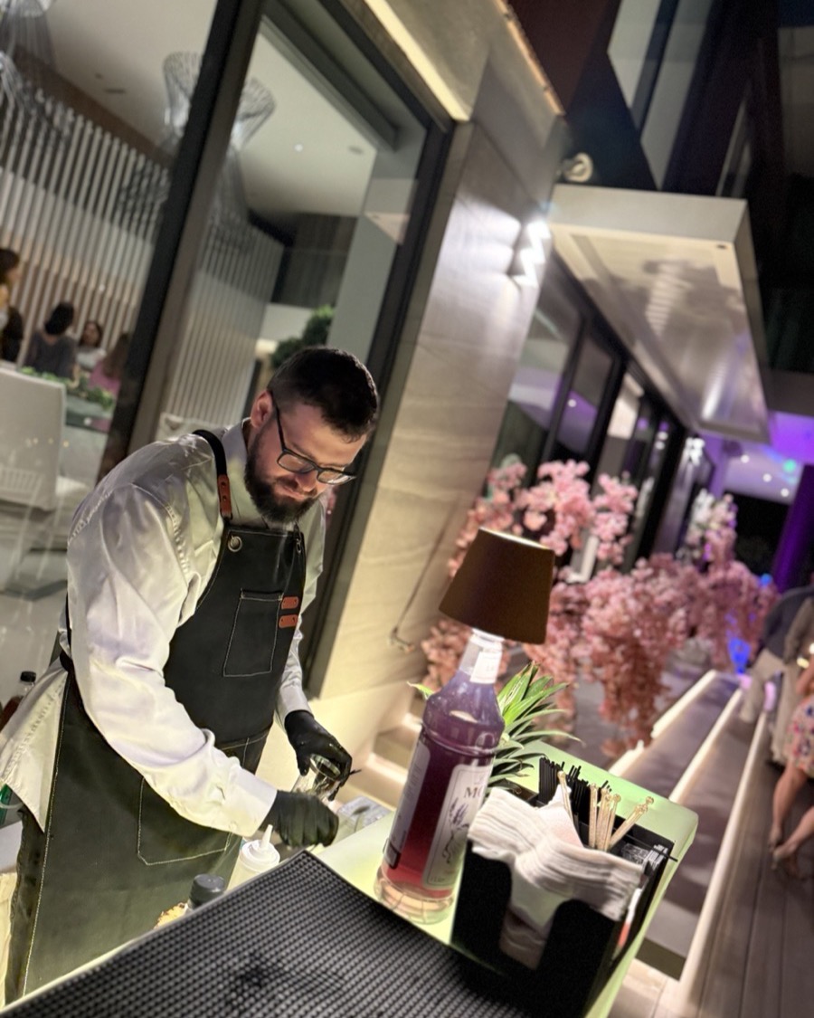 Bartender mixing colorful mocktails at bar Miami party