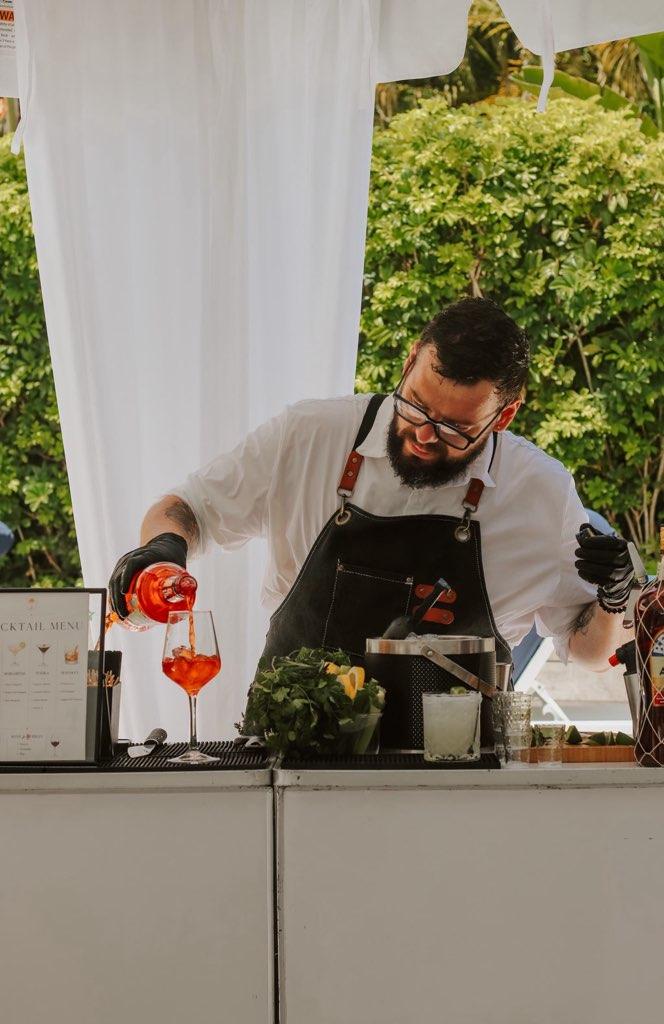 Bartender pouring an Aperol Spritz into a wine glass at a Miami daytime event