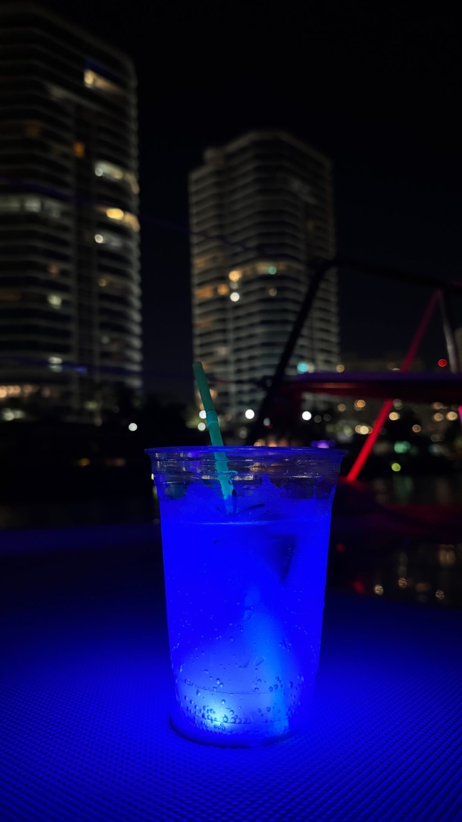 Blue cocktail held against the Miami skyline from a yacht